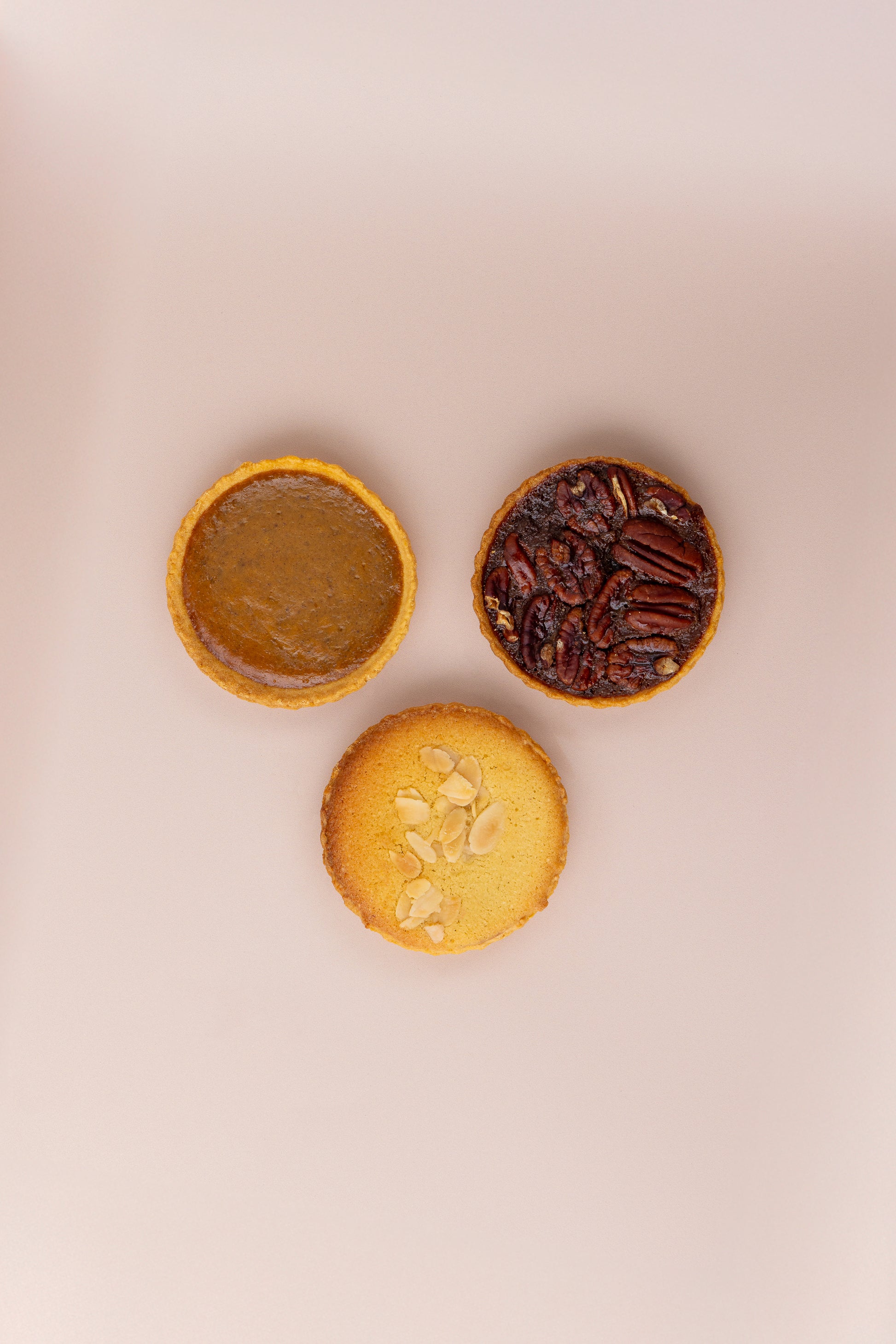 Three mini tartlets on a beige background