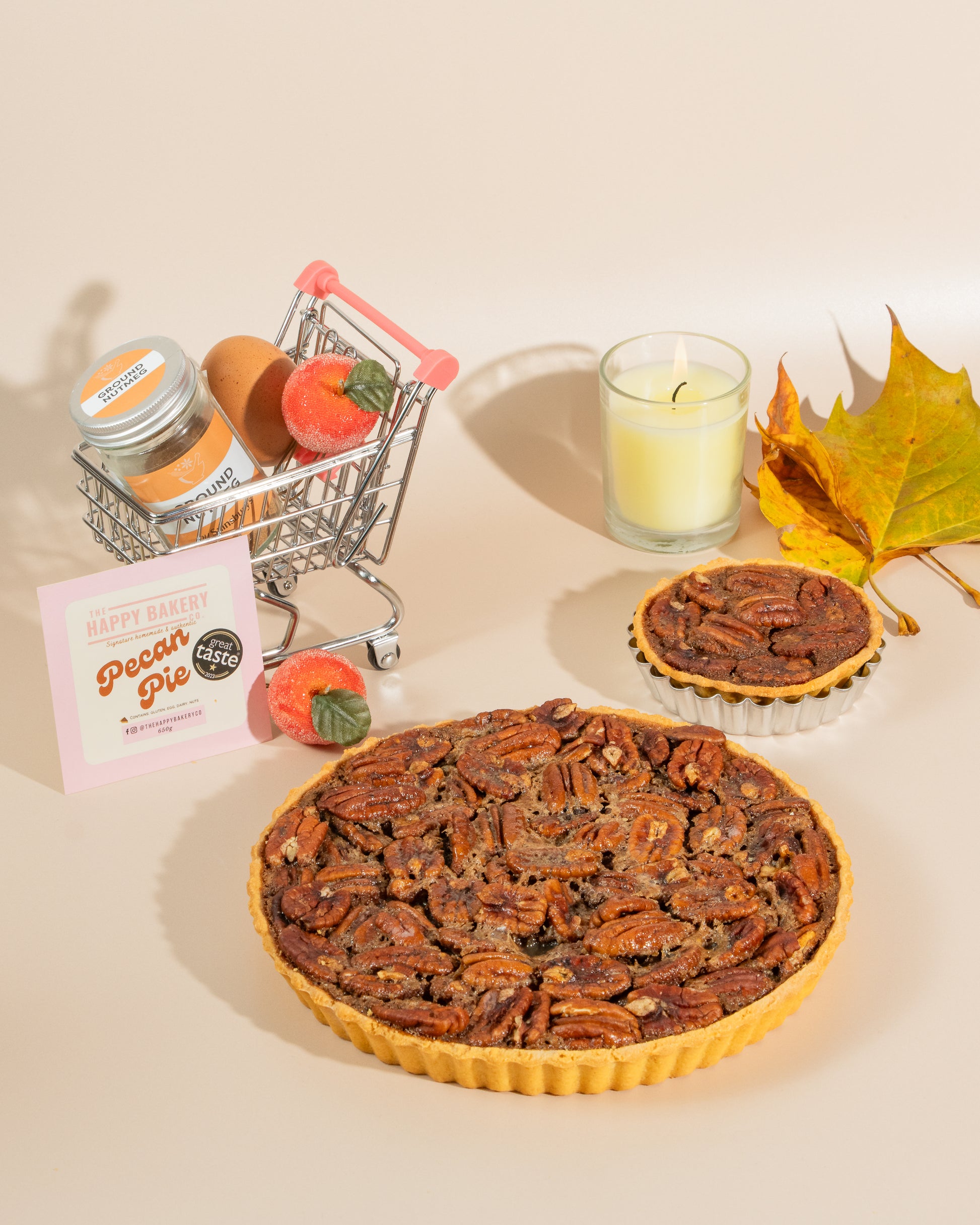 Pecan pie with a, mini shopping cart, and candle on a beige background